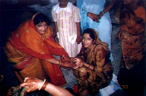 Ma looks up while applying haldi